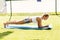 Perfect plank. Full-length side view of young beautiful woman in sportswear doing plank while standing on the greed lawn