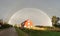 Perfect rainbow over the rural houses and a field after the rain