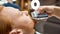 Perfect shape. Close up shot of a young redhead guy visiting barbershop, getting beard haircut by professional barber