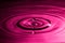 Perfect water drop splashing into smooth water causing ripples in a pink colour