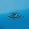 Perfect water droplet creating ripples on serene blue surface