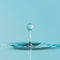 Perfect water droplet suspended above a serene blue surface