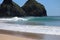Perfect waves in cristaline waters beside Two Brothers Cliff, Cacimba beach, Fernando de Noronha island, Brazil