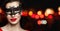 Perfect woman face in black carnival mask and red lips makeup on black background with abstract night glitter bokeh