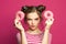 Perfect young woman with donuts on vivid pink background, diet concept
