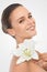 Perfecting perfection. Studio beauty shot of an attractive brunette woman holding a flower.