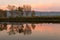 A perfectly symmetric view of a lake, with trees reflections on water at sunset