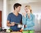 Perfecto. Shot of a handsome young man giving his wife a taste of his cooking.