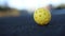 Perforated ball for pickleball rolling on the court ground in slow motion video clip