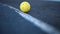 Perforated plastic ball for pickleball rolling on court in slow motion