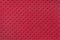 Perforated red leather texture background, closeup. Dark backdrop from wrinkle skin