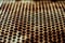 Perforated rusty iron sheet. Surface of industrial mesh with depth of field. Horizontal corrosion grunge background