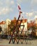 A performance artist balances on top of a house of cards