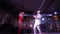 Performance on the stage of two artists. Singer is in red swimming suit and guitarist in white suit. They are jumping