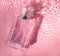Perfume bottle on the background and water drops. A bottle of perfume without inscriptions . Smell. Perfume on a pink