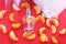 Perfume bottle for women on a red background, decorated with Mandarin slices. The concept of a fresh citrus perfume