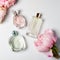 Perfume bottles with flowers on light background. Perfumery, cosmetics, fragrance collection. Flat lay