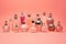 perfume bottles. a lot of transparent multi-colored glass bottles of cosmetics on a pink background. ai generative