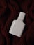 Perfume in a glass grey bottle on a dark brown knitted sweater as background. Toilet water, still life. Flat lay