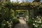 pergola covered in climbing roses and surrounded by lush greenery