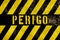 Perigo in Portuguese language, danger warning sign text with yellow and dark stripes painted over concrete wall facade texture