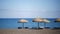 Perissa beach covered with black sand view with sunbeds and umbrellas on Santorini, Greece