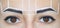 Permanent make-up for eyebrows of beautiful woman with thick brows in beauty salon.