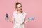 Perplexed young woman housewife in apron hold atomizer spray with washing cleanser cleaning rag while doing housework