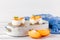 Persimmon creamy trifle in beautiful glasses, fresh ripe fruit slices on white wooden background. Healthy vegetarian food. Delicio