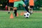 Persistent teen boy in sportswear trains football on soccer field and learns to circle the ball between training cones.