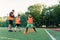 Persistent teen sports boys in orange uniform running among plastic cones during football exercises at the stadium.