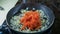 Person adds grated carrot to fried onion