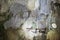 Person admiring a wall inside a cave in natural light as provided by a hole in the ceiling. Cave formations and small stalactites