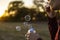 Person blow soap bubbles on a sunset in nature field f