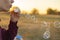 Person blow soap bubbles on a sunset in nature field f