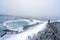 Person with blue jacket ovelooking ice covered Viti volcanic crater near Krafla geothermal area in Iceland.