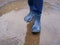 A person in boots standing in a muddy puddle