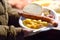 Person buy portion fried potatoes and sausages in disposable plate on famous open air Christmas fair in Krakow. Street food on