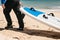 Person carries a surfboard on the beach