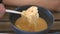 Person catches shrimp in soup with white spoon closeup