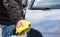 Person cleaning the front of a car with a yellow rag