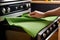 Person Cleaning Kitchen Oven Surface with Green Microfiber Cloth and Detergent Spray