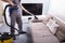 Person Cleaning Sofa With Vacuum Cleaner