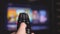 a person controls TV using a modern remote control. A man watches a smart TV and uses a black remote control. blurry tv