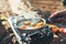 Person cooking fried eggs in nature camping outdoor, cooker prepare scrambled breakfast picnic on metal gas stove, tourism