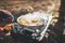 Person cooking fried eggs in nature camping outdoor, cooker prepare scrambled omelette breakfast picnic on metal stove, tourist