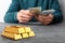 Person counting money at table, focus on stacked gold bars.