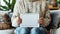 Person in a cozy sweater holding a tablet with a blank screen.