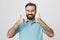 Person with cute beard and moustache thumbs up to show his positive answer standing near white wall. Mature male wearing