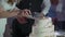 A person cutting a celebration cake. Bride and groom at wedding reception venue.